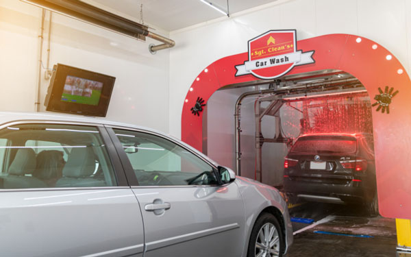 vehicles entering car wash tunnel with a nopileups display on the wall