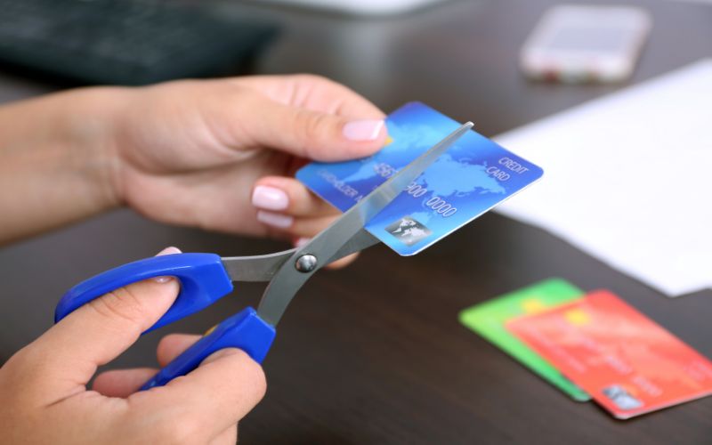 close up of hands starting to cut a credit card with scissors