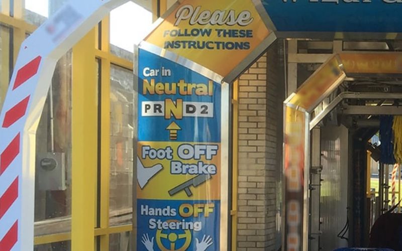 sign inside car wash tunnel instructing customers to keep car in neutral and foot off the brake