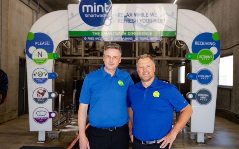 Jim Gunderson and Chris Friesen posing inside a Mint Smartwash car wash tunnel