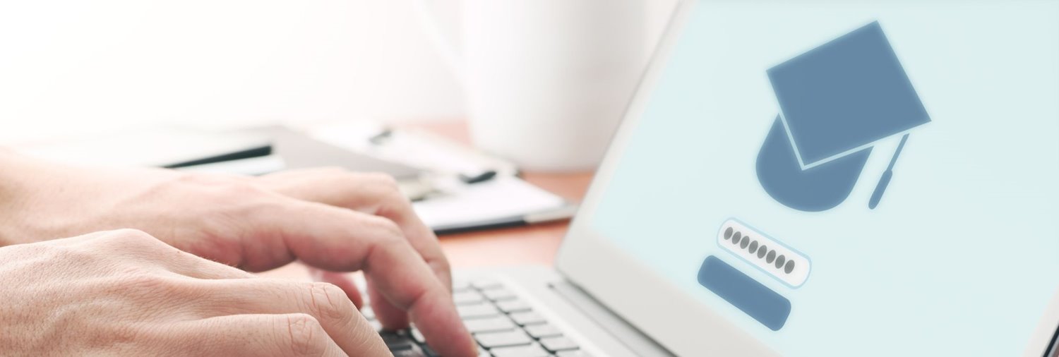 hands on laptop computer with a graduation cap on the screen