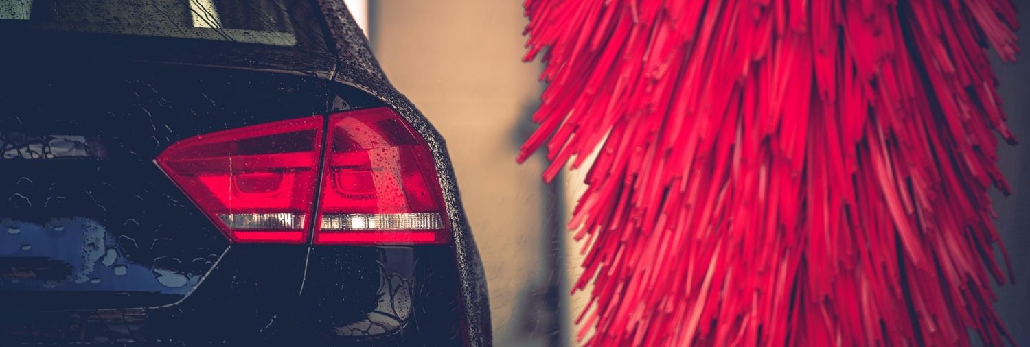 wet passenger side taillight of a black car going by a red car wash wrap