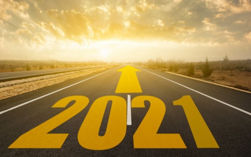 2021 in large yellow font and a large yellow arrow pointing up overlaid on an image of a road