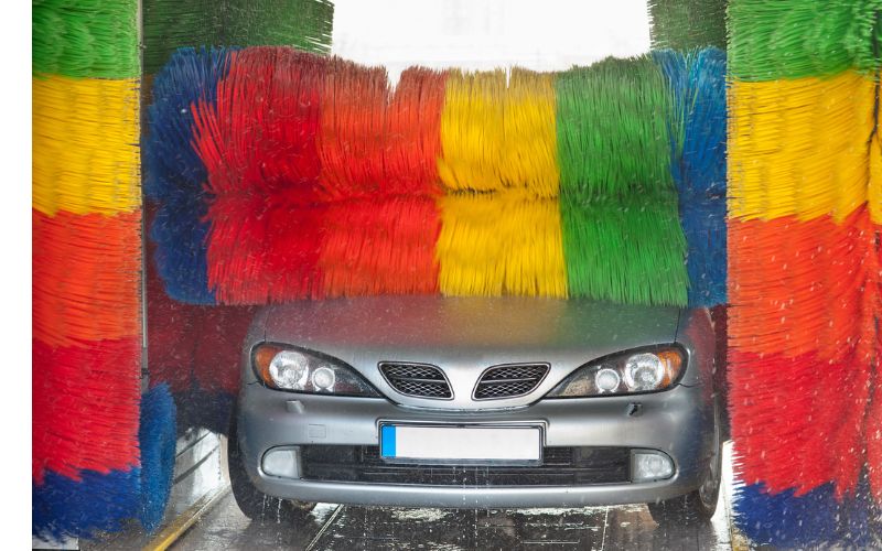 vehicle in in-bay car wash with colorful brushes