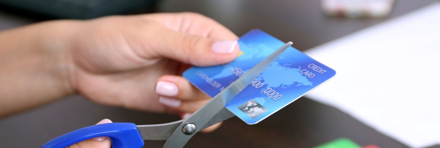 close up of hands starting to cut a credit card with scissors