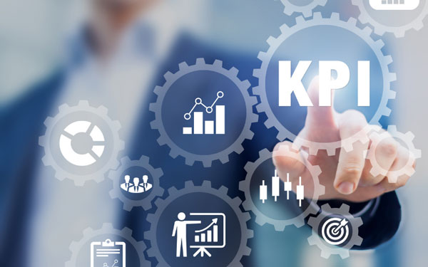 A man in the background in a blue sportscoat pointing at a gear that says KPI