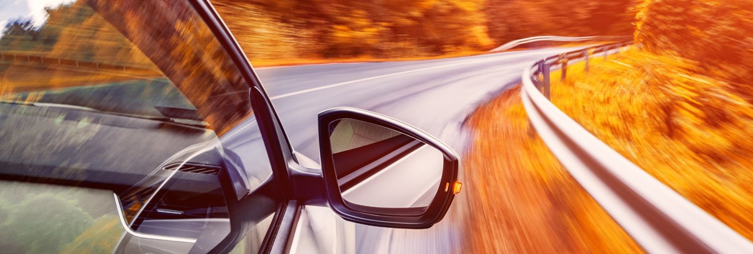 vehicle going down a road lined with fall foliage