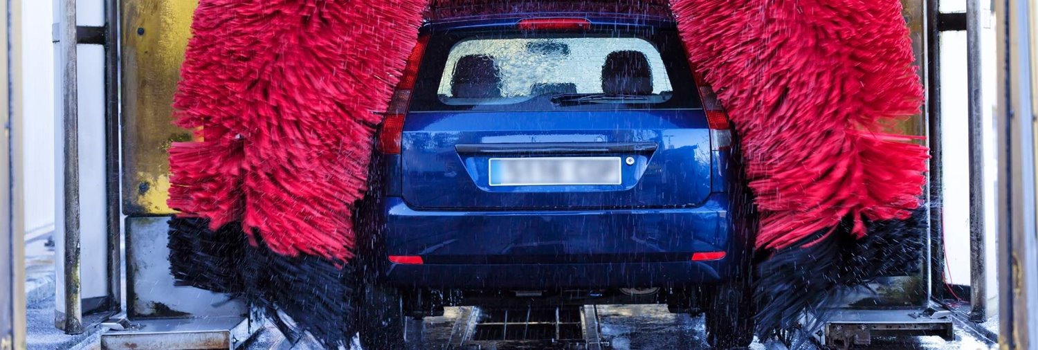 rear end of blue car inside a running in-bay automatic car wash