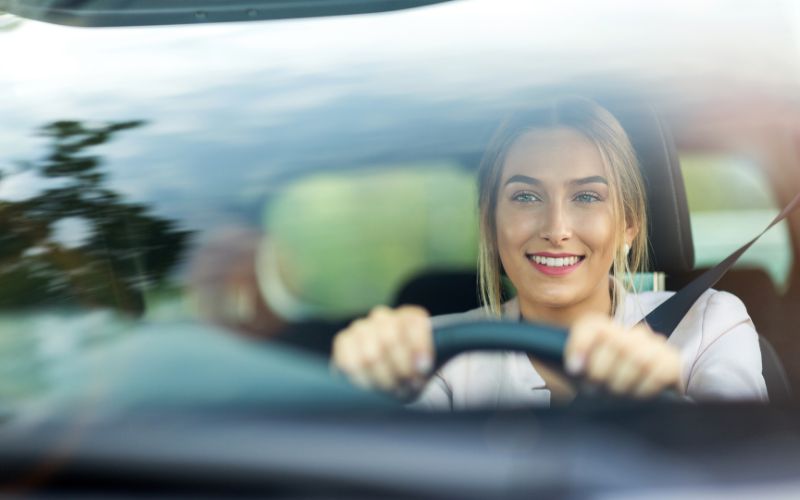 image through windshield showing smiling woman driving