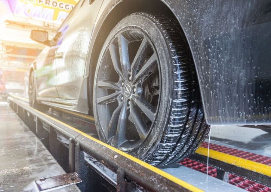 car going through car wash tunnel with focus on the back driver side wheel