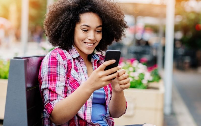 woman sitting on bench looking at phone