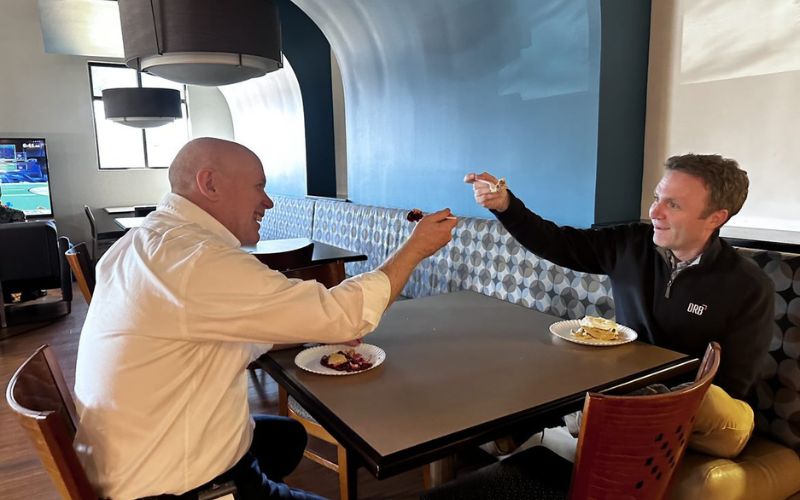 two drb employees smiling and lifting forkfulls of pie